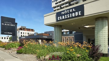 Entrada de un hotel con un cartel que dice "HOTEL CLASSIQUE" y "COSMOS" cerca.