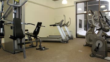 Un gimnasio con diferentes equipos de ejercicio, incluyendo cintas de correr, bicicletas estáticas y máquinas de pesas.