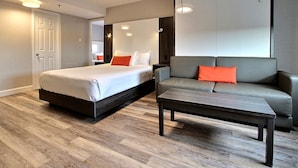A modern hotel room with a large bed, a sofa, a coffee table, and a wardrobe. - Hotel Classique (Québec City)
