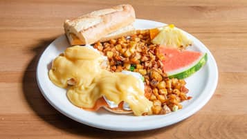 A plate with eggs benedict, hash browns, a slice of watermelon, and a piece of toast.