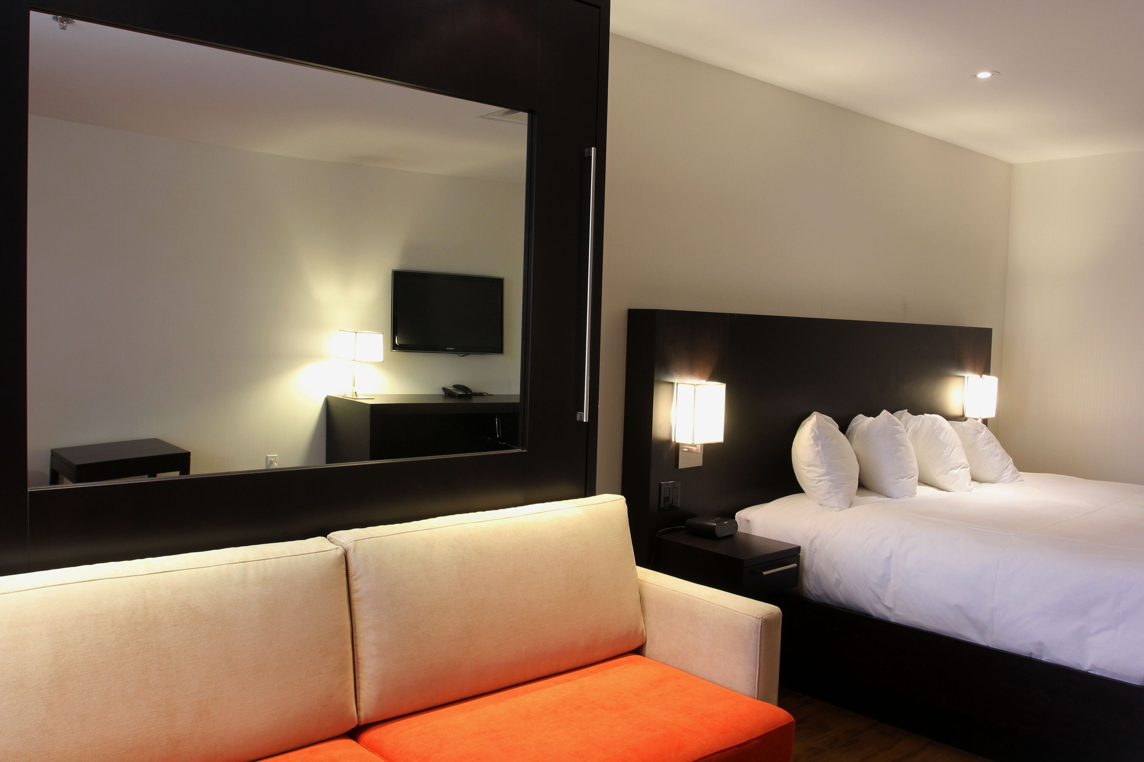 Een hotelkamer met een groot bed, een bank, een televisie en een spiegel.