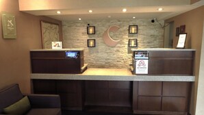 A reception desk with a stone wall backdrop, framed pictures, and a 'No Smoking' sign. - Comfort Inn Dartmouth (Dartmouth)
