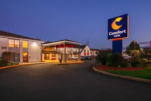Un hotel Comfort Inn con una entrada bien iluminada, un área de estacionamiento y un letrero grande.