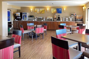 A hotel dining area with multiple tables and chairs, a coffee station, and a view of the cityscape. - Comfort Inn Dartmouth (Dartmouth)
