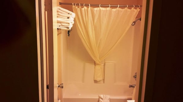 A bathroom with a bathtub, a shower curtain, and a towel rack with towels.