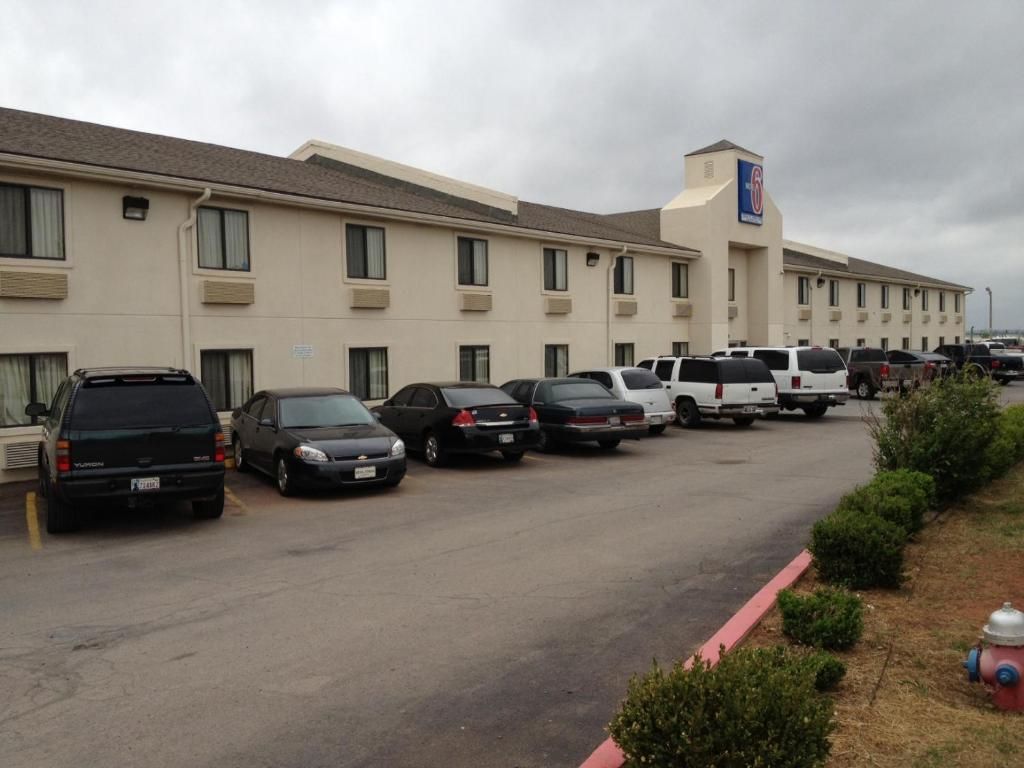 A parking lot with several cars parked in front of a hotel with a sign indicating it is a 6-star establishment.