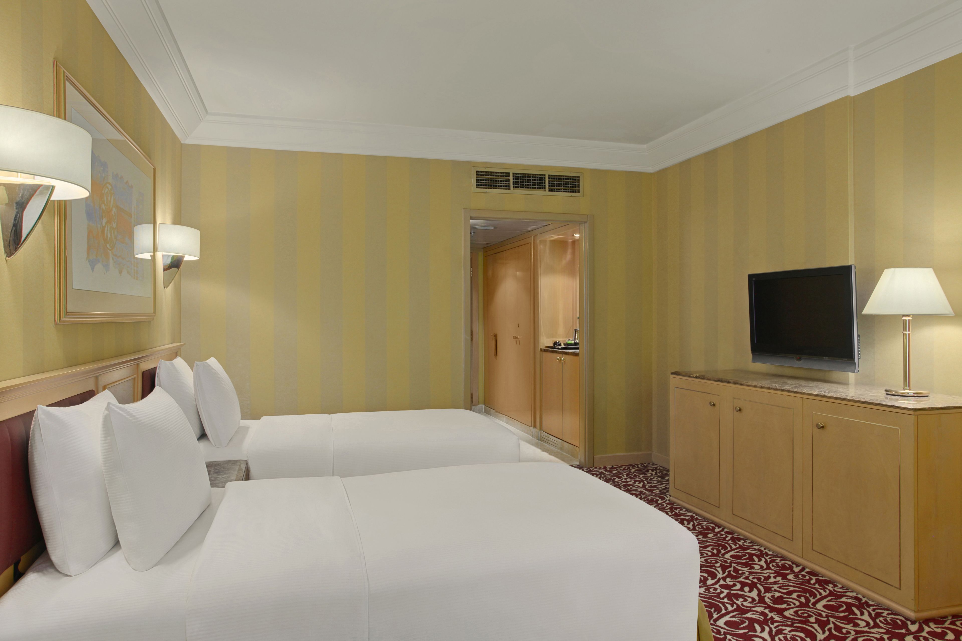 A hotel room with two beds, a television, and a cabinet.