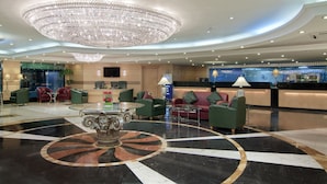 A hotel lobby with a large chandelier, a reception desk, and modern furnishings.