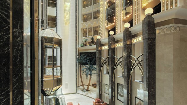 A spacious lobby with a central atrium, marble columns, and a decorative fountain.