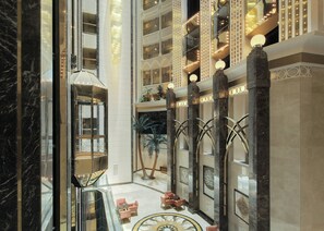 Un amplio vestíbulo con un atrio central, columnas de mármol y una fuente decorativa.