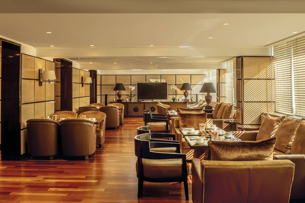 Un hall d’hôtel spacieux, doté d’un long comptoir d’accueil, de plusieurs espaces salon et d’un grand téléviseur à écran plat.