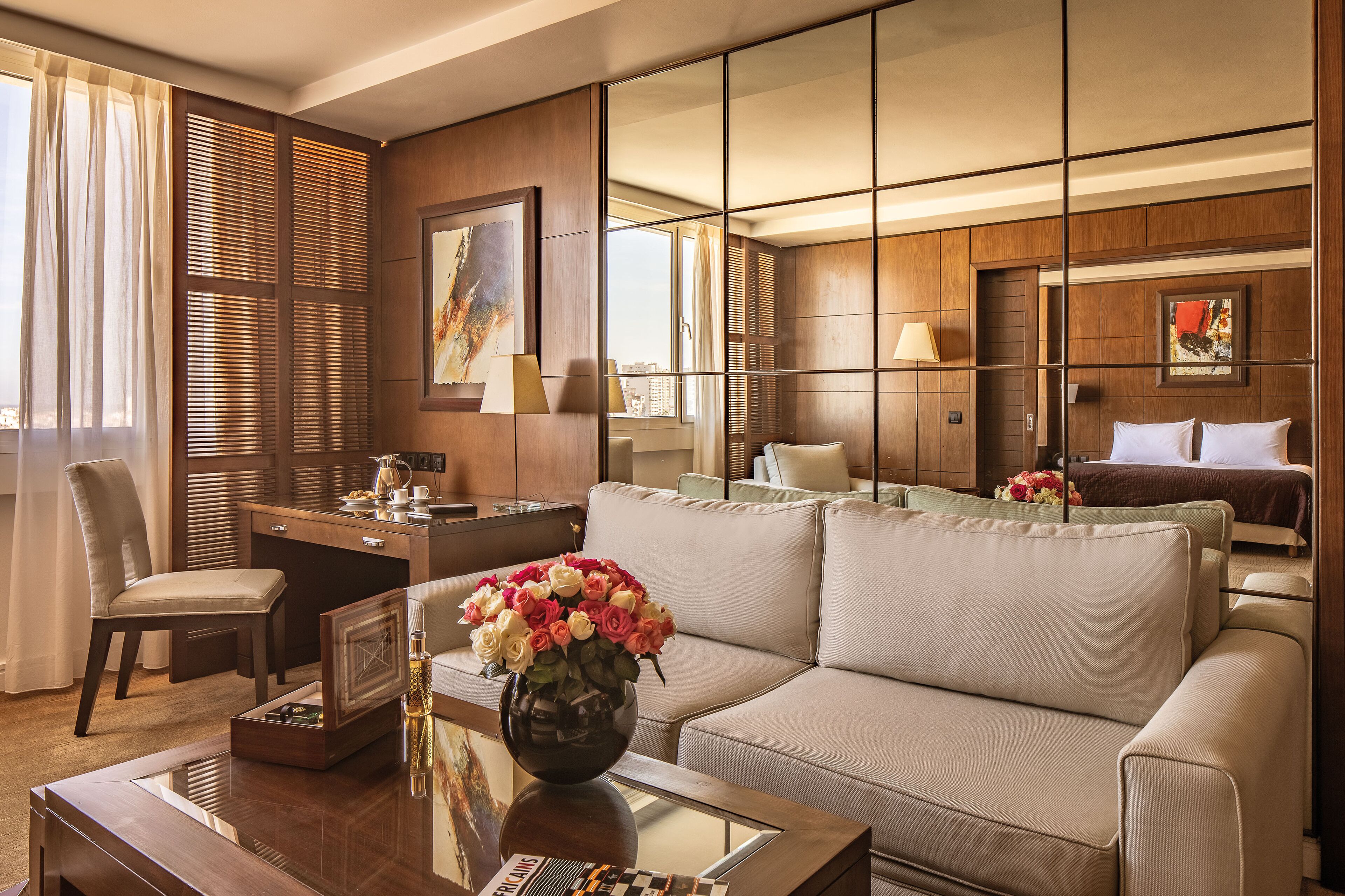 Ein Hotelzimmer mit Sofa, Schreibtisch, Stuhl, Couchtisch und Bett.