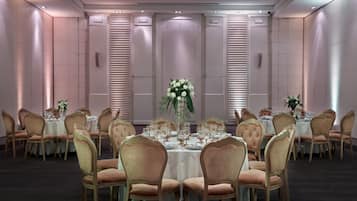 Une salle à manger élégante, avec des tables rondes, des chaises et des centres de table floraux.