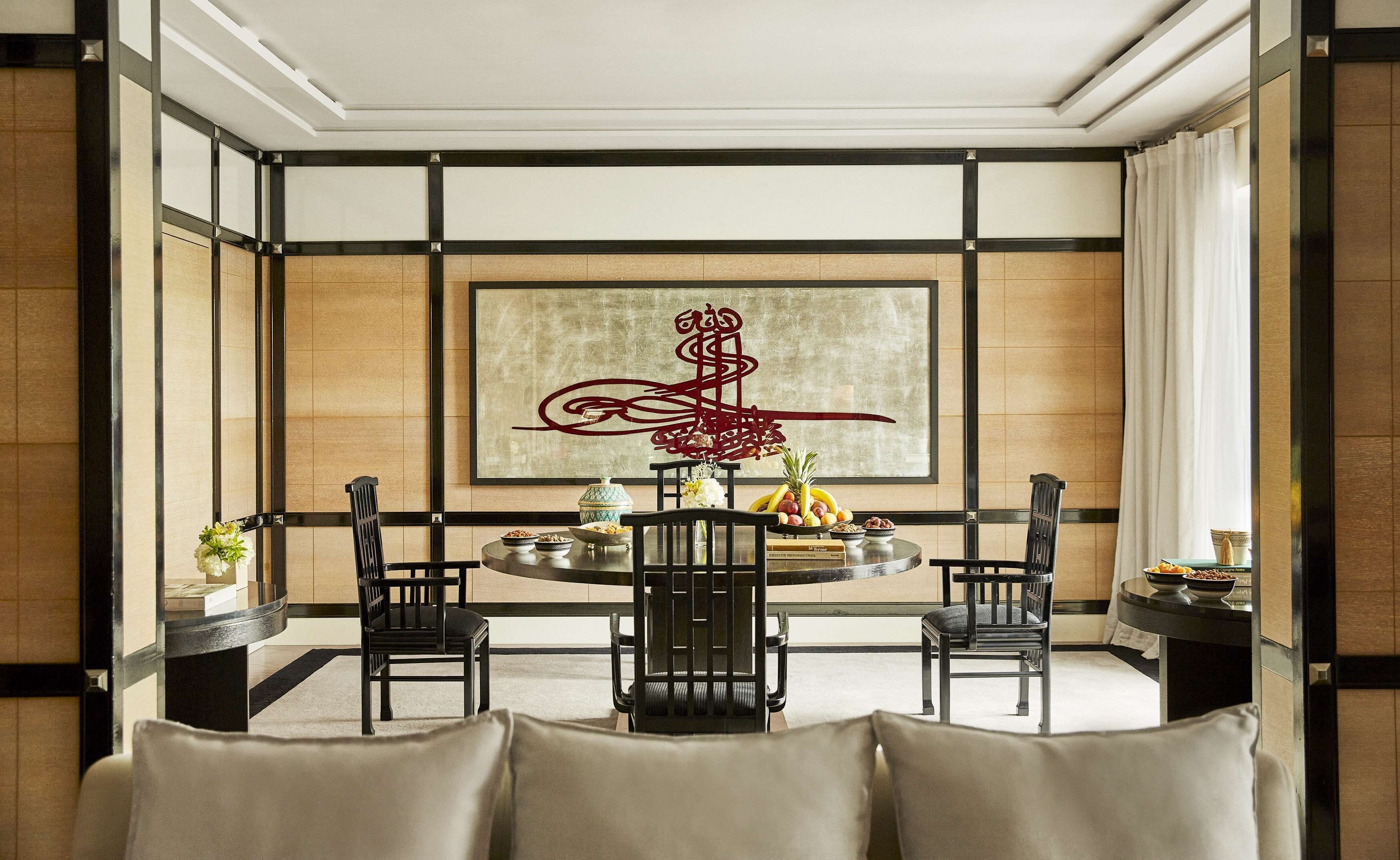 A dining room with a round table, four chairs, and a large abstract artwork on the wall.
