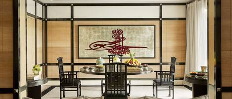 A dining room with a round table, four chairs, and a large abstract artwork on the wall.