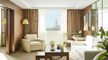 Una habitación de hotel moderna con un ventanal grande, dos sofás, una mesa de centro y paneles de madera.