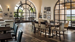 A spacious dining area with high ceilings, large windows, and a view of the ocean. - Hilton Santa Barbara Beachfront Resort (Santa Barbara)