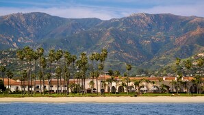 A coastal hotel with a beach view, palm trees, and mountainous background. - Hilton Santa Barbara Beachfront Resort (Santa Barbara)
