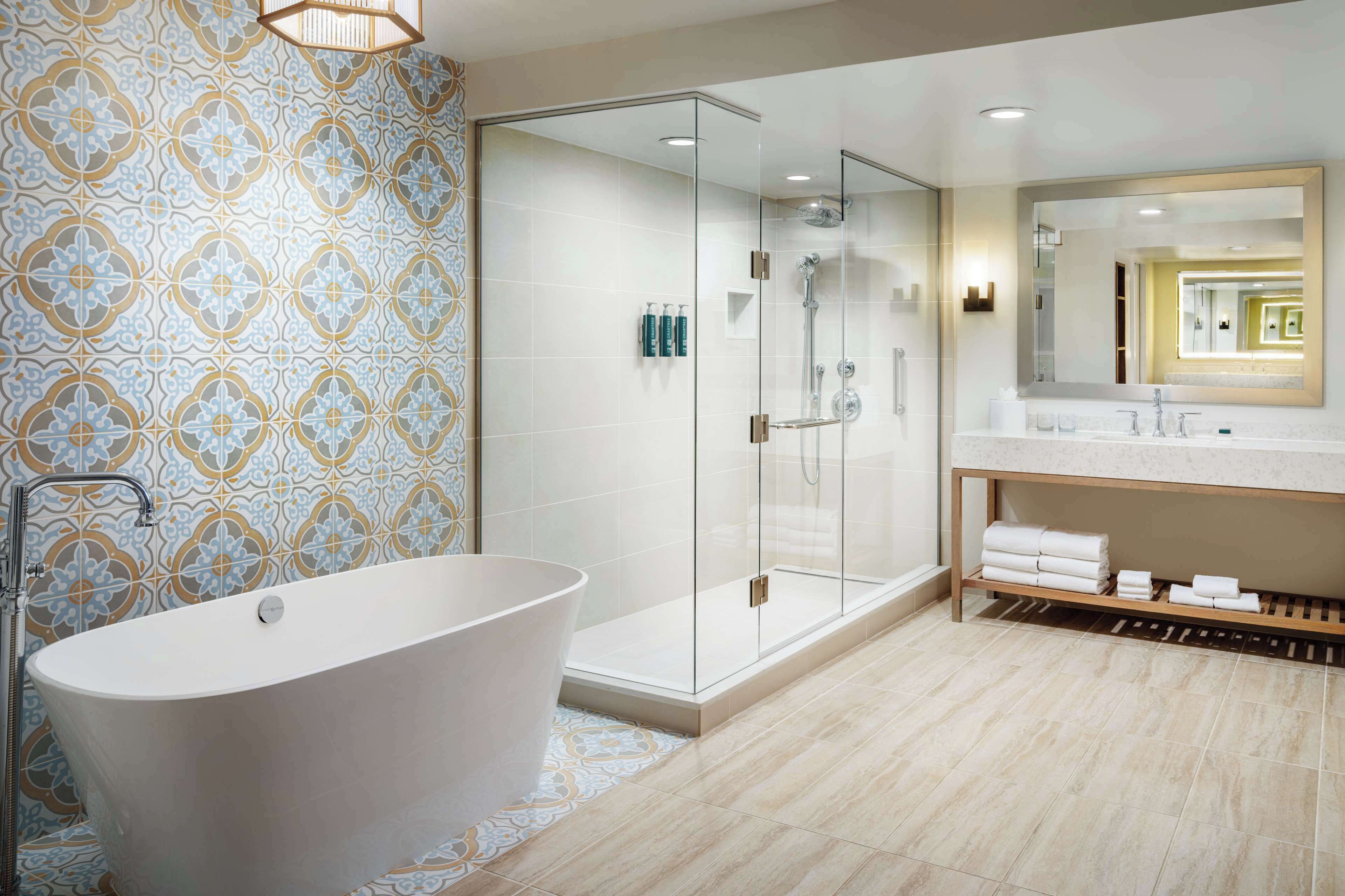 Une salle de bain moderne avec une baignoire sur pieds, une douche à parois de verre et un meuble-lavabo avec un miroir.