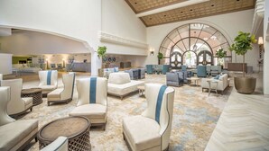 A spacious lobby with modern seating, a high ceiling, and a large arched window. - Hilton Santa Barbara Beachfront Resort (Santa Barbara)