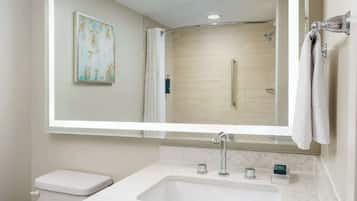 Une salle de bain moderne avec un grand miroir, un lavabo, des toilettes et un espace douche.