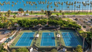 A tennis court complex with multiple courts, surrounded by palm trees and a beach view. - Hilton Santa Barbara Beachfront Resort (Santa Barbara)