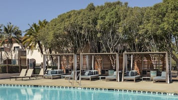 Un área junto a la piscina con sillones de descanso y una pérgola.