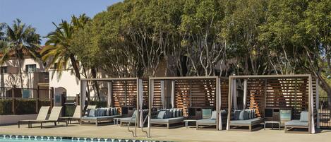 A poolside area with lounge chairs and a pergola.