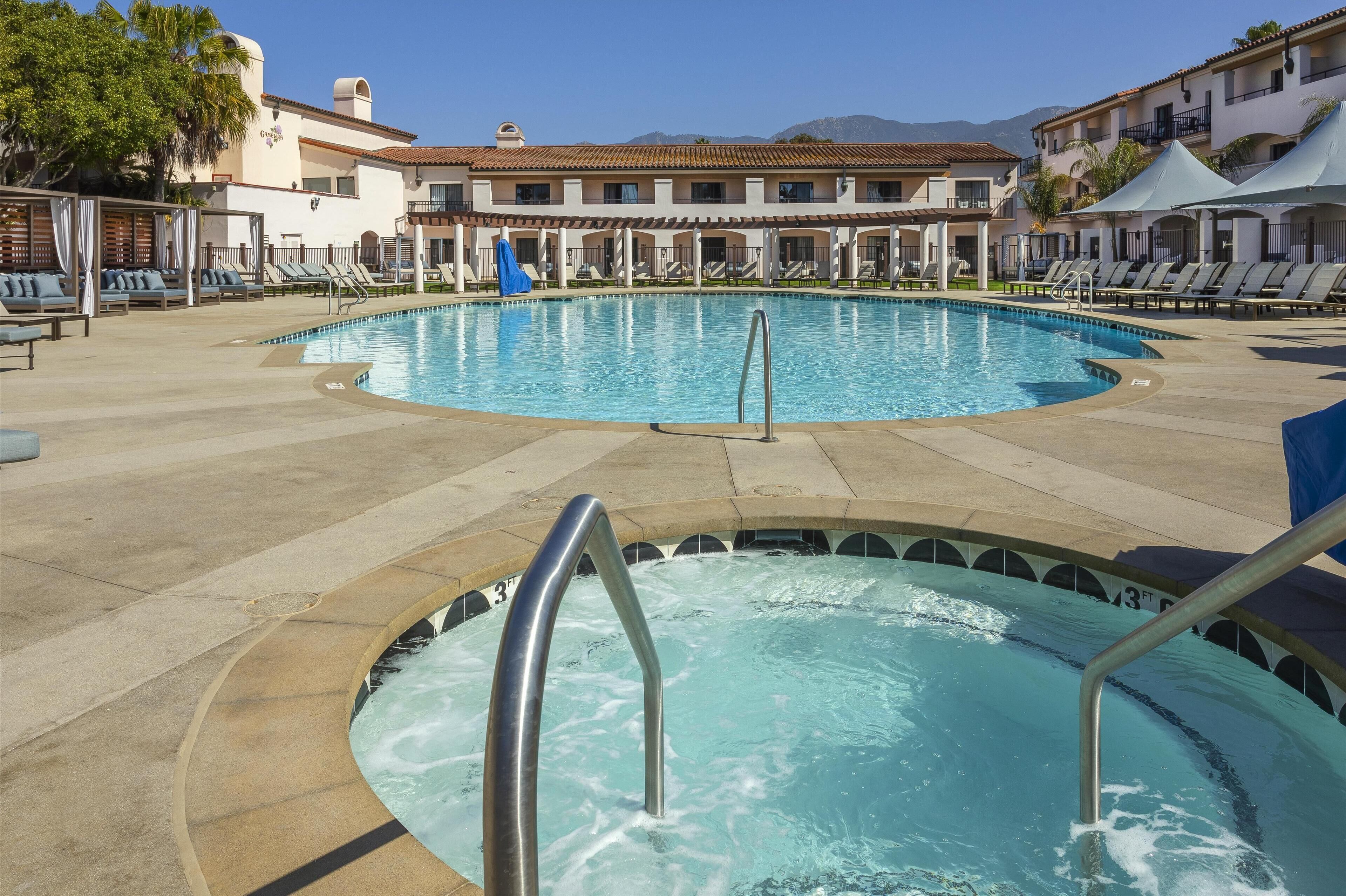 A pool area with lounge chairs and a hot tub.