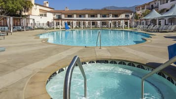 A pool area with lounge chairs and a hot tub.