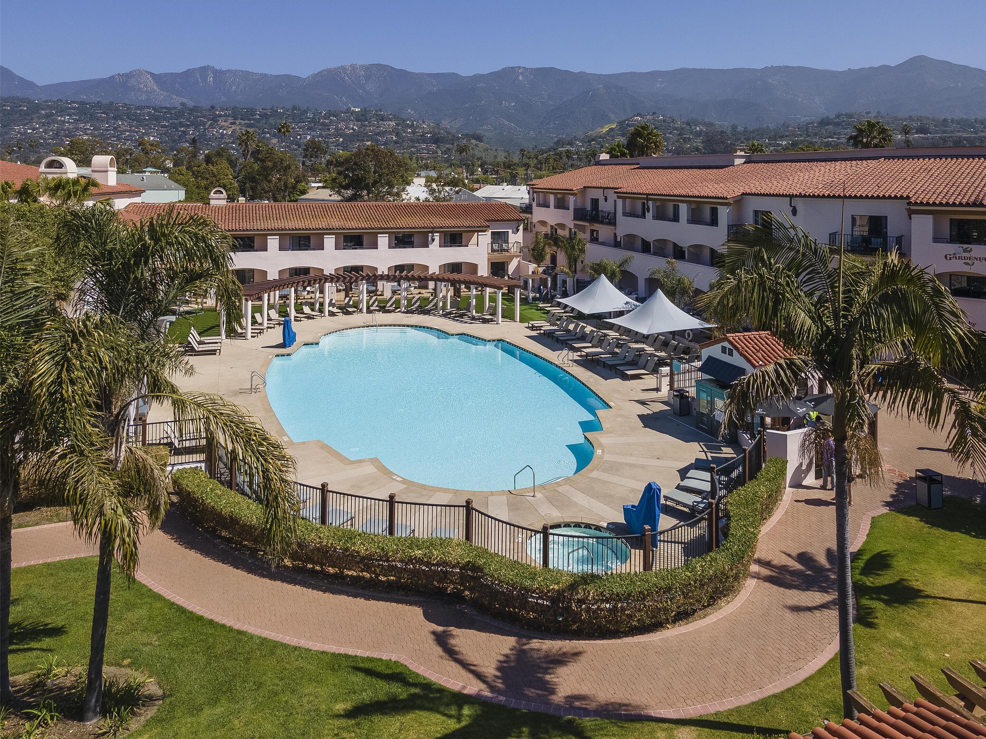 Un resort con una amplia piscina, sillas de descanso y vistas a las montañas.