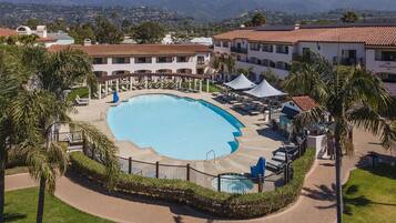 Un resort con una amplia piscina, sillas de descanso y vistas a las montañas.
