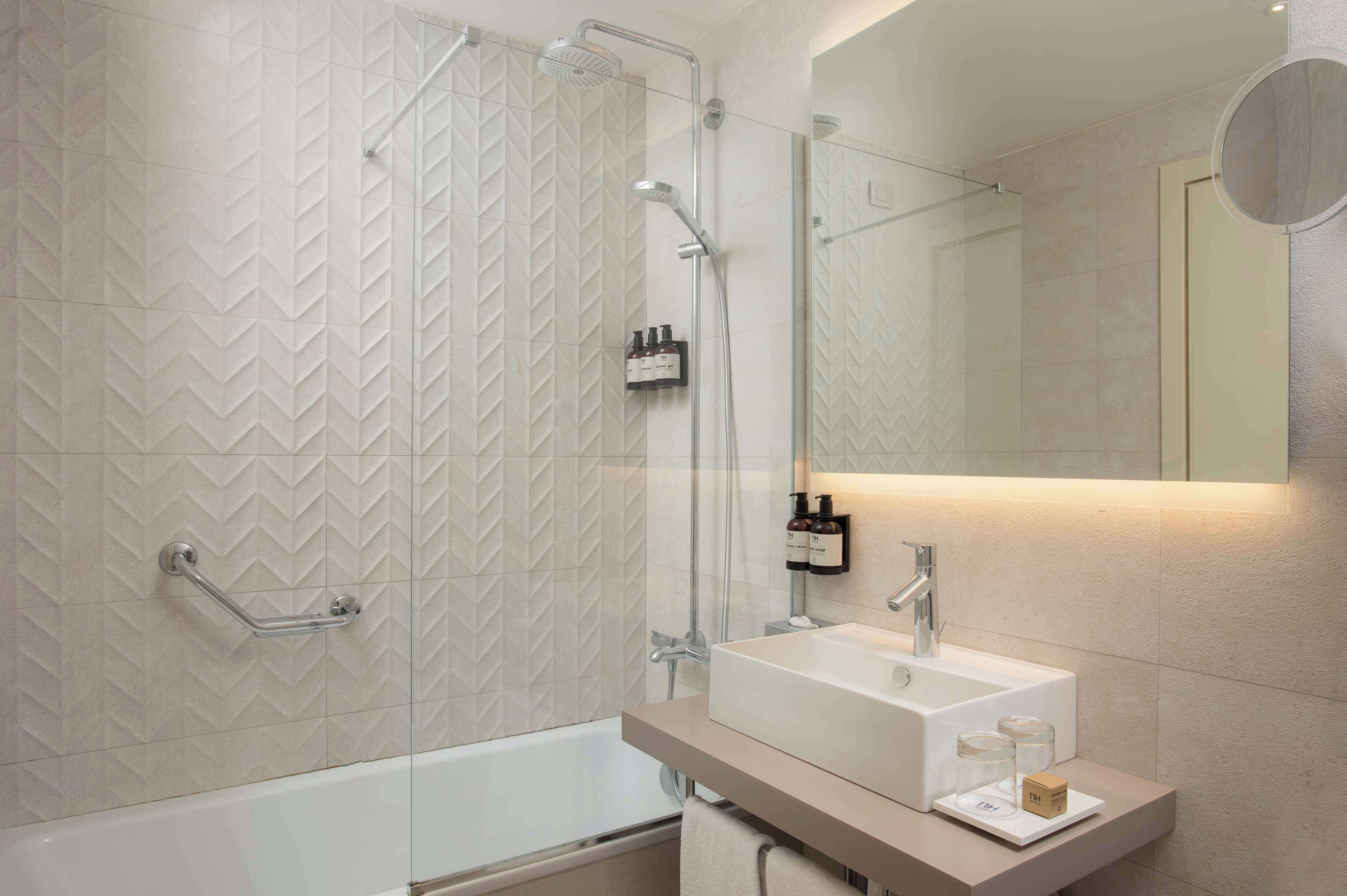 A modern bathroom with a shower, a sink, and a mirror.
