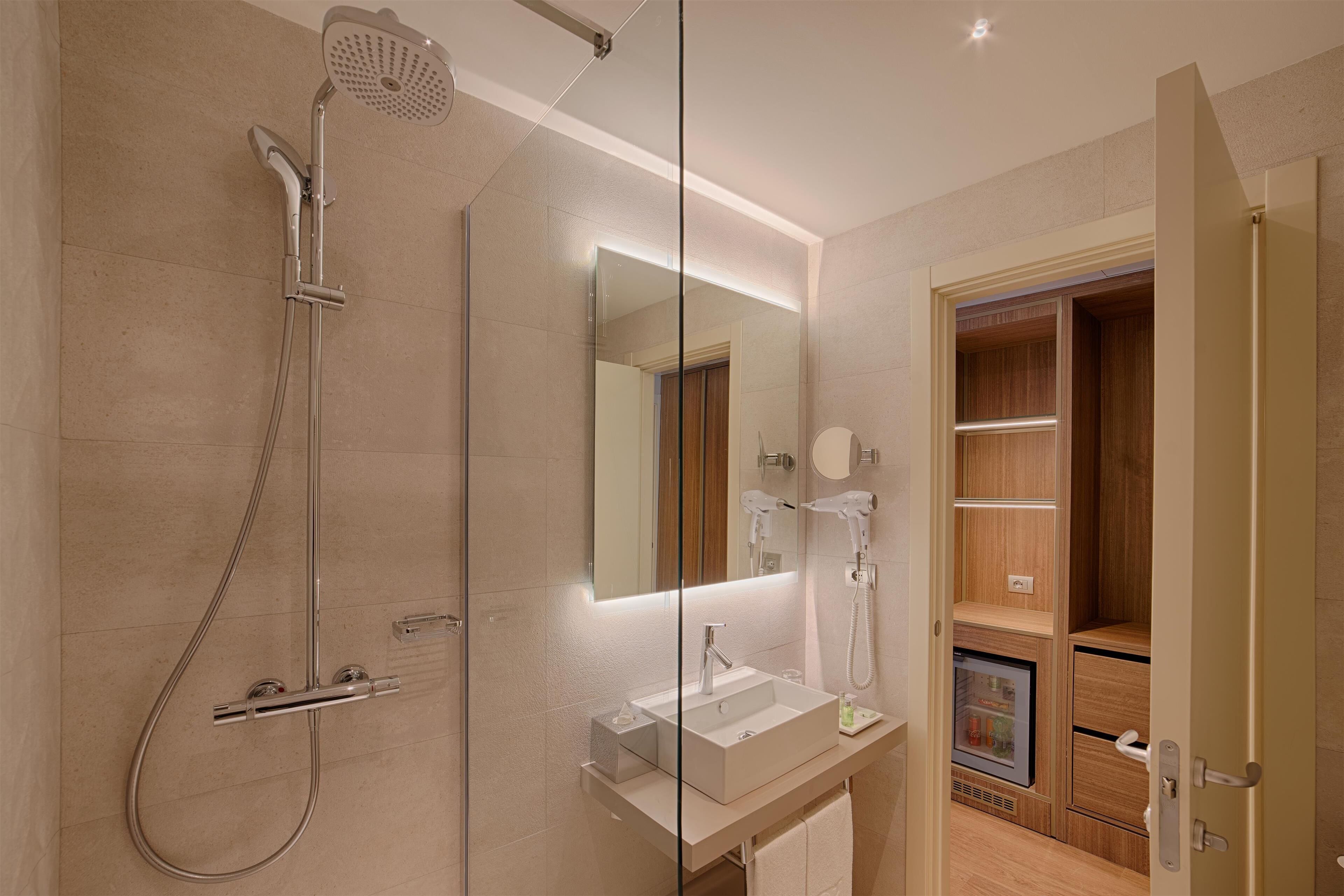 Une salle de bain moderne dotée d’une douche à parois de verre, d’un meuble-lavabo avec miroir et d’un sèche-cheveux intégré.