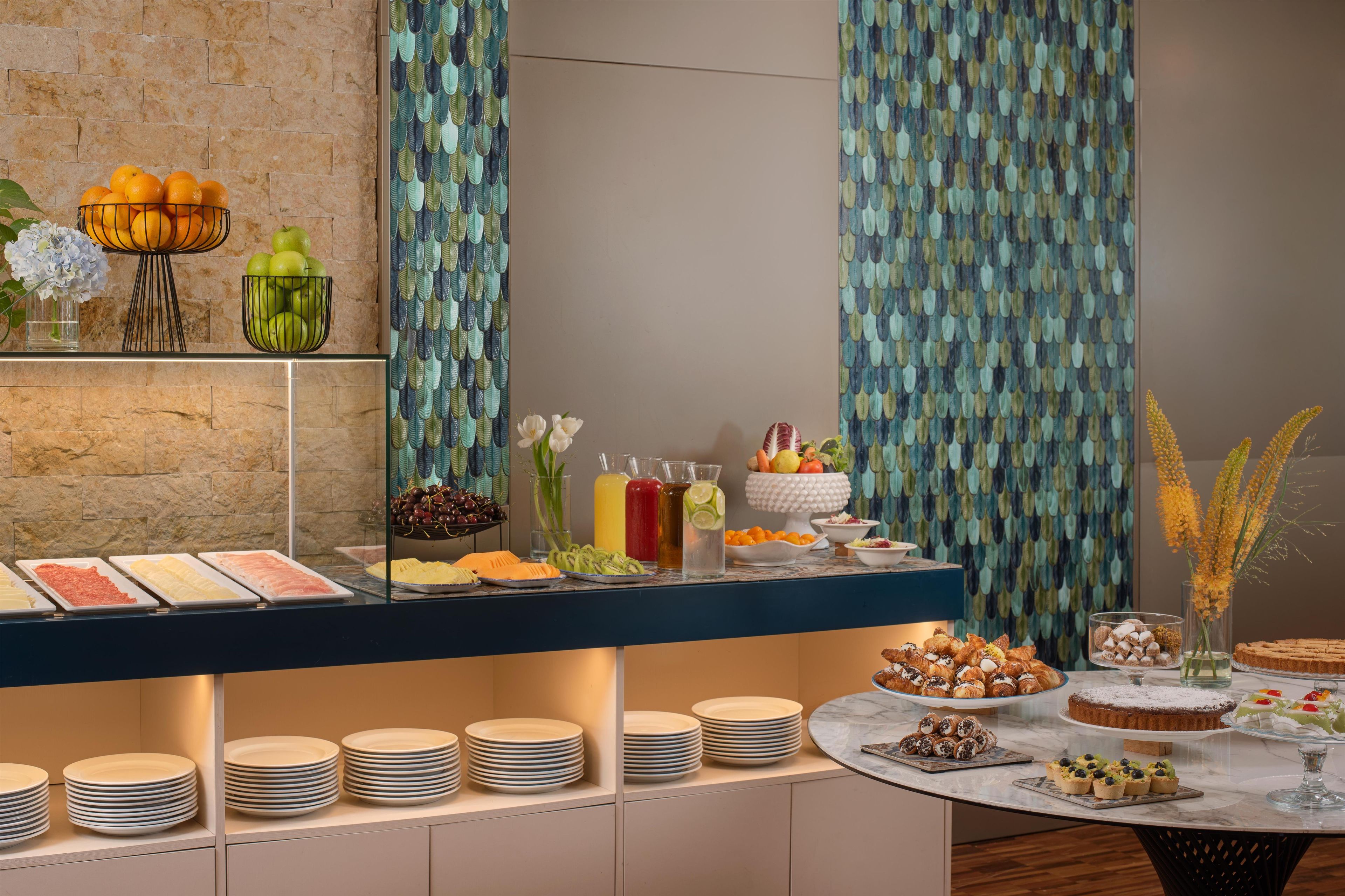 A buffet setup with various food items and beverages, including fruits, pastries, and a selection of drinks.
