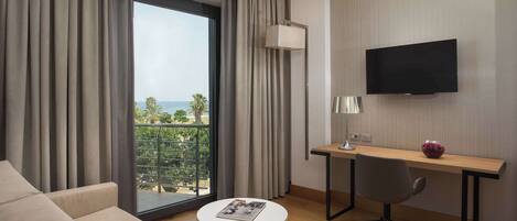 Une chambre d’hôtel moderne dotée d’une grande fenêtre, d’un canapé, d’un bureau avec une chaise et d’un téléviseur à écran plat.