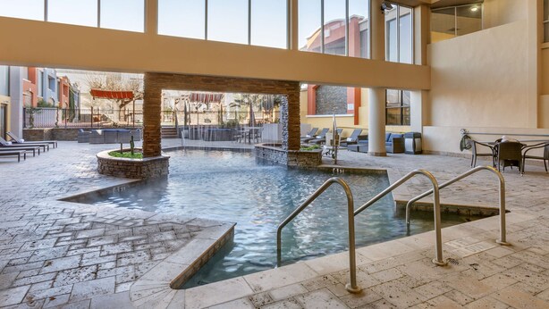 An indoor pool area with a stone fountain, lounge chairs, and a view of the outside.