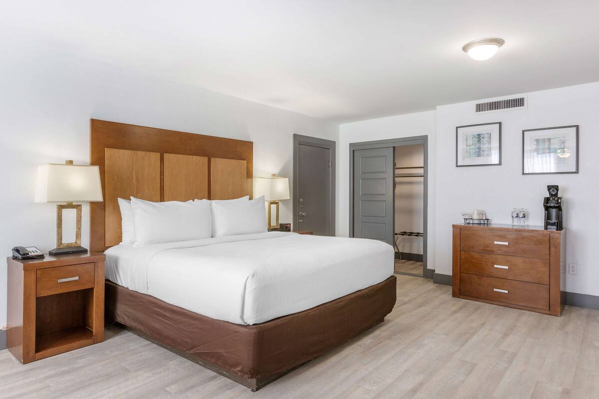 Een hotelkamer met een groot bed, nachtkastjes, een dressoir en ingekaderde foto's aan de muur.