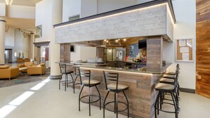 A modern bar area with a high counter, bar stools, and a seating area with sofas and a coffee table.