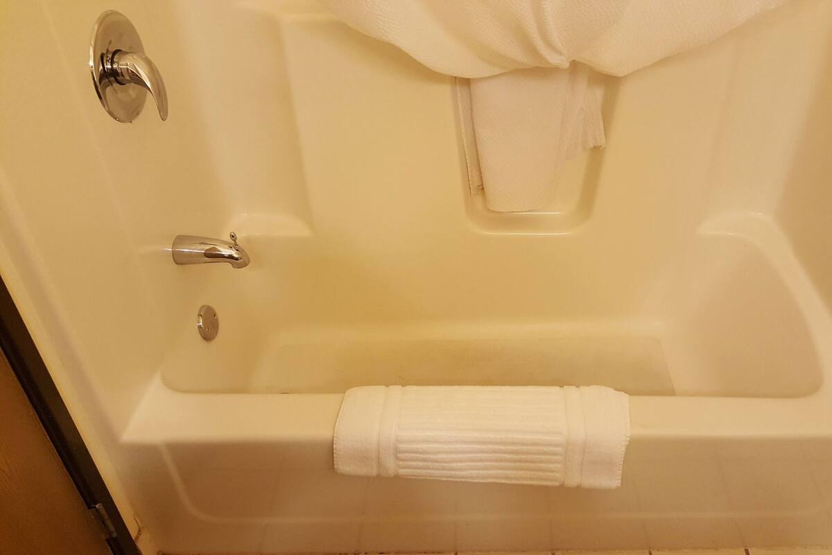 A white bathtub with a towel, a faucet, and a showerhead.