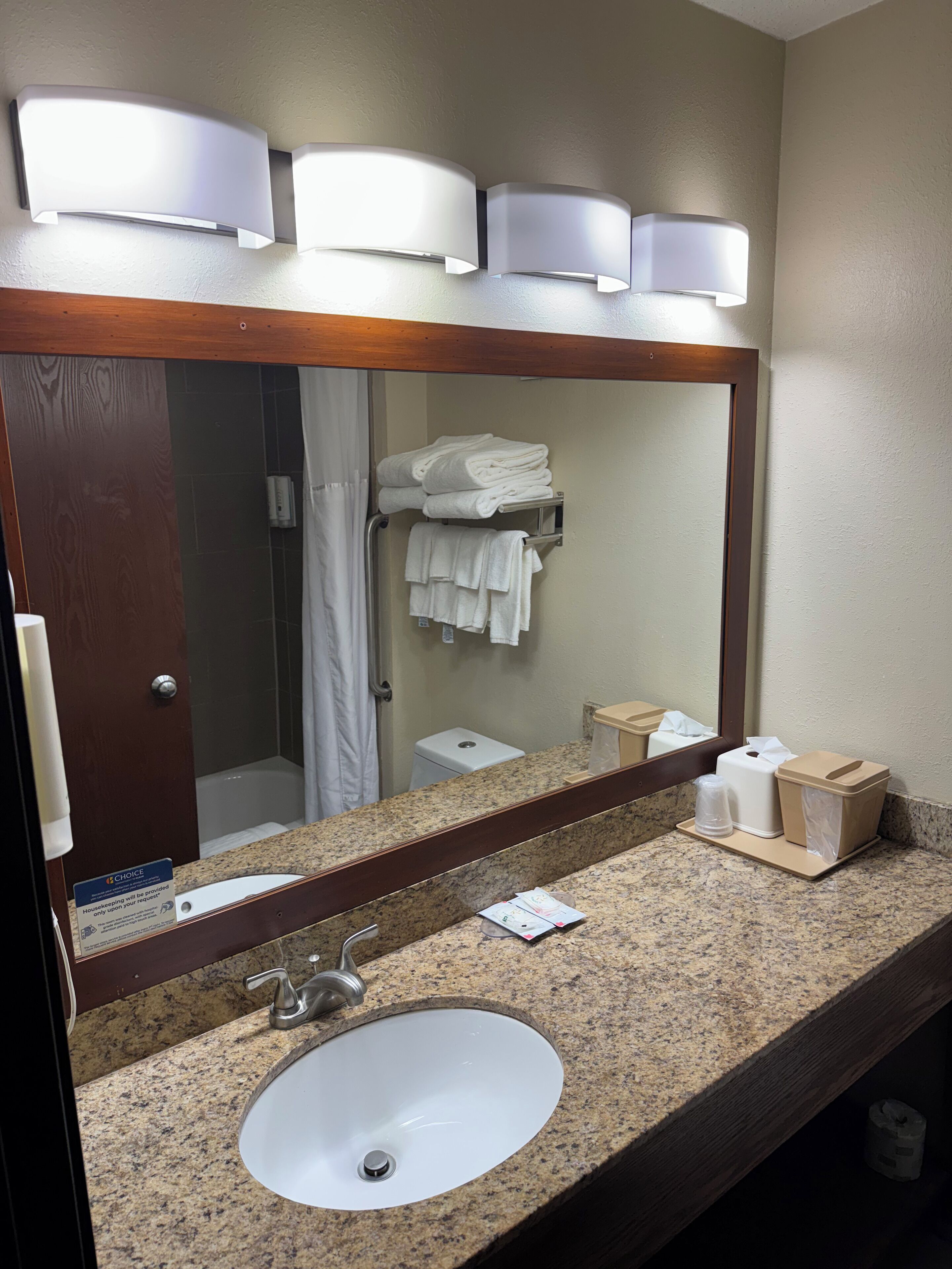 A bathroom with a granite countertop, a sink, a mirror, and a towel rack with folded towels.