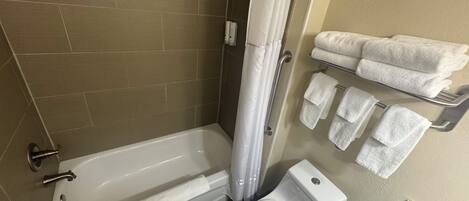 A bathroom with a bathtub, toilet, and a towel rack with towels.