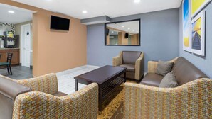 Un salón moderno con un sofá, sillones, una mesa de centro y un televisor montado en la pared.