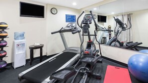 Un gimnasio con cintas de correr, elípticas, dispensador de agua y pelotas de ejercicio.