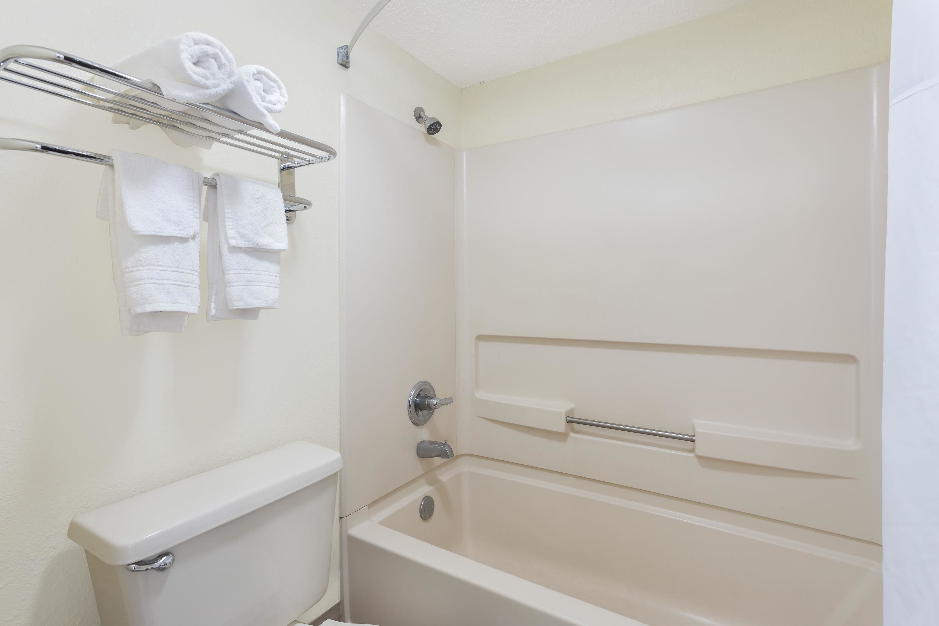 A bathroom with a toilet, a bathtub, and a towel rack with towels.