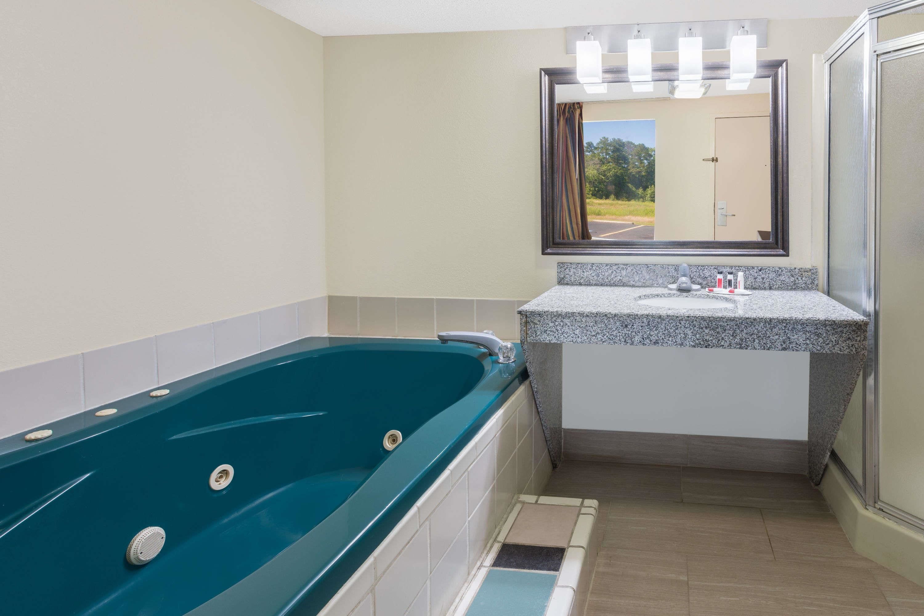 Un baño con una bañera grande, un lavabo y un espejo.