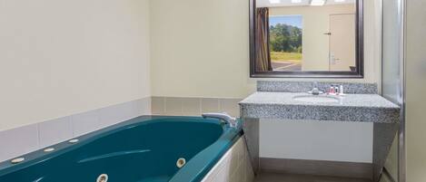 A bathroom with a large bathtub, a sink, and a mirror.