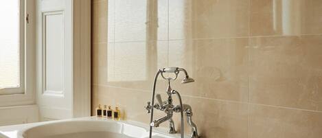 A bathroom with a large bathtub, a shower, and a mirror.