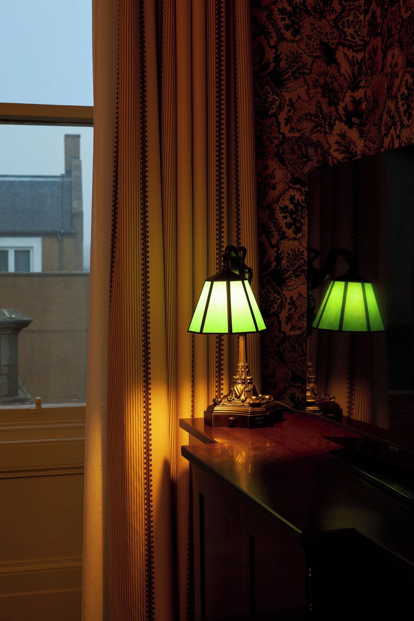 A room with a window, curtains, and two table lamps.