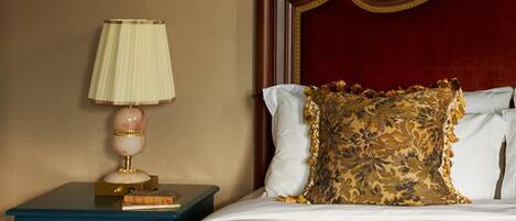 A neatly made bed with a red headboard, a decorative pillow, and a lamp on a nightstand with a 'SEA' sign.